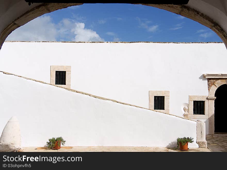 A white Portuguese villa with an arch and stairs