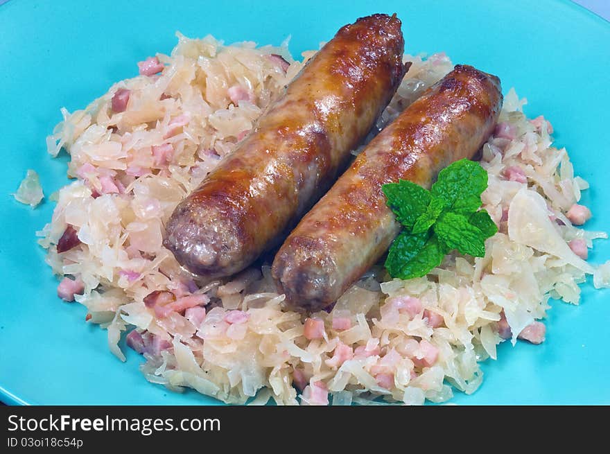 Two sausages on a plate with sauerckraut