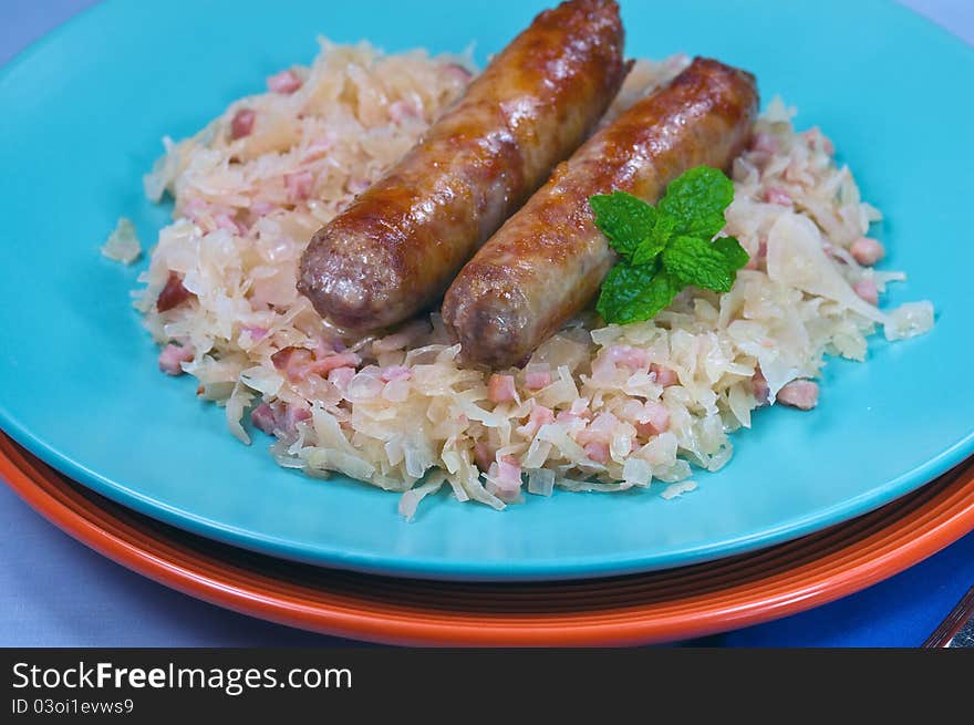 Two sausages on a plate with sauerckraut