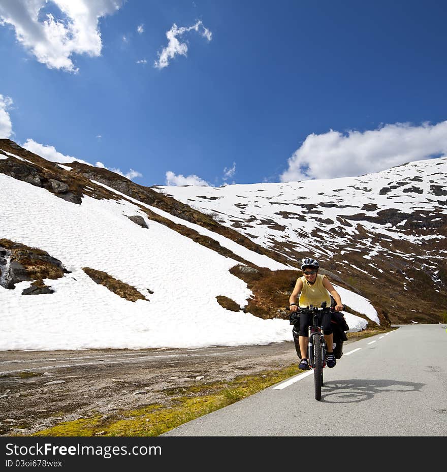 Girl biking in high mountains in Norway. Girl biking in high mountains in Norway