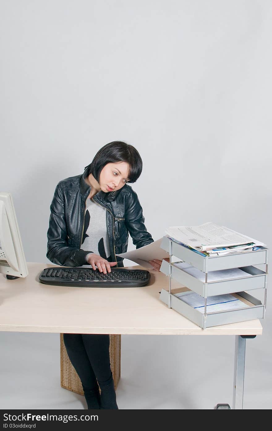 Girl sitting at desk on telephone reading papers. Girl sitting at desk on telephone reading papers