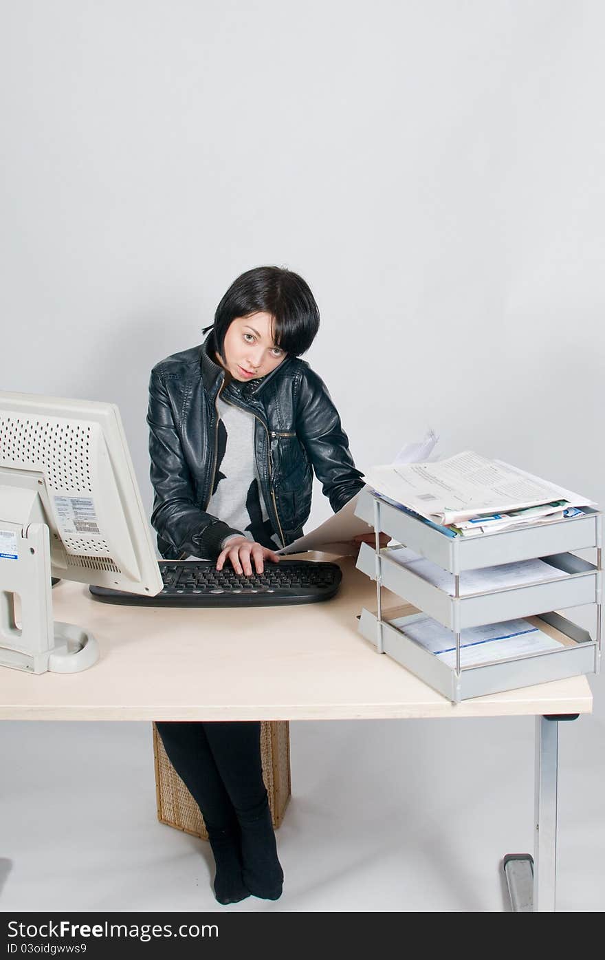 Girl sitting at desk on telephone reading papers. Girl sitting at desk on telephone reading papers