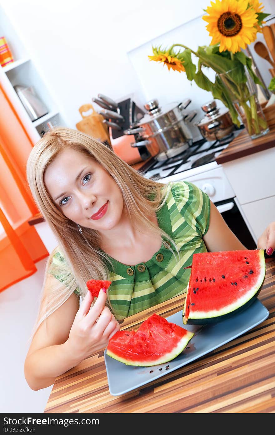 Young woman eating watermelon in the kitchen. Young woman eating watermelon in the kitchen