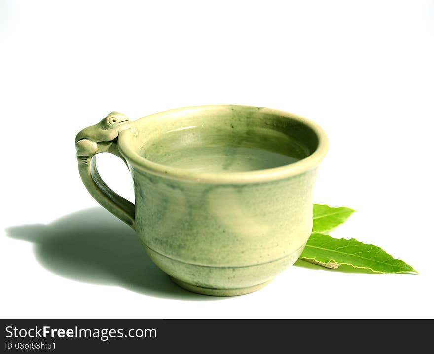 A nice hand-crafted cup of tea with focus on the frog and the leafs. On a white backgrpund. A nice hand-crafted cup of tea with focus on the frog and the leafs. On a white backgrpund