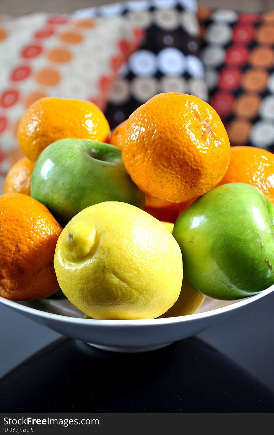 Mandarins, oranges, apples and lemons in a ceramic bowl, on a home background. Mandarins, oranges, apples and lemons in a ceramic bowl, on a home background