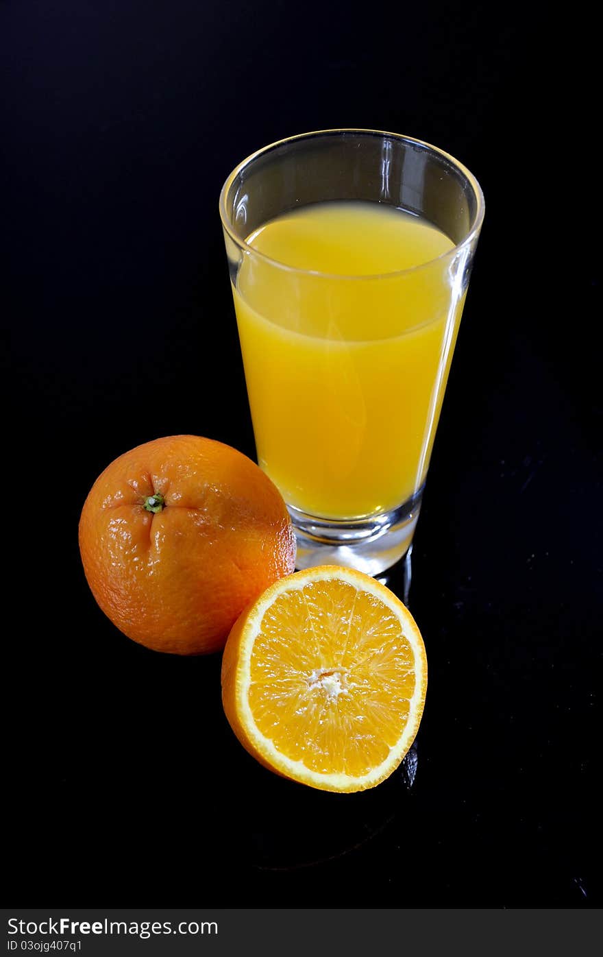 Orange juice glass and sliced orange on a black background