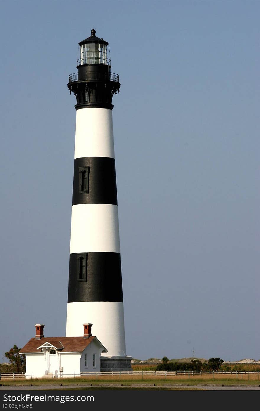 Black and White striped lighthouse against gray-blue sky, no clouds. Black and White striped lighthouse against gray-blue sky, no clouds