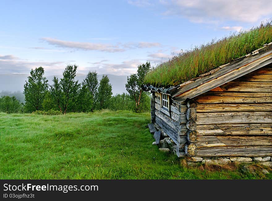 Part of a small house with growing grass on the roof. Part of a small house with growing grass on the roof.