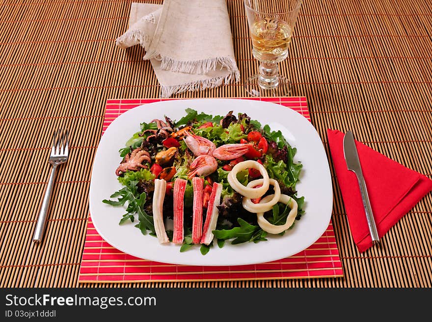 Italian frutti di mare salad spaghetti pasta on table with white wine glass, knife and fork. Italian frutti di mare salad spaghetti pasta on table with white wine glass, knife and fork