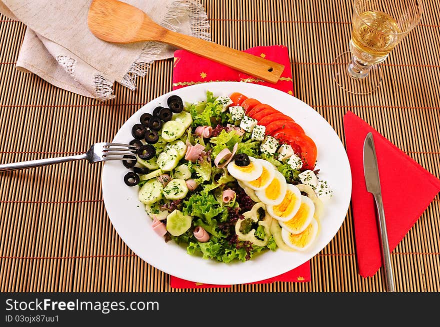 Italian Cesar salad on table with white wine glass, knife and fork