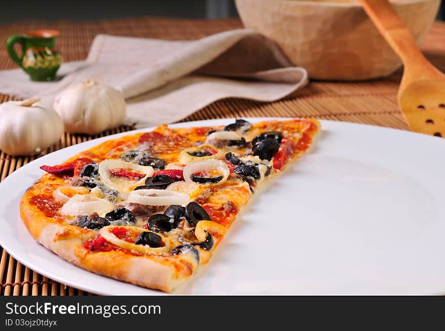 Italian pizza slice on table with garlic and olives