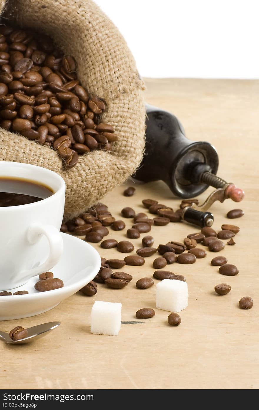 Cup of coffee and grinder with beans on white background