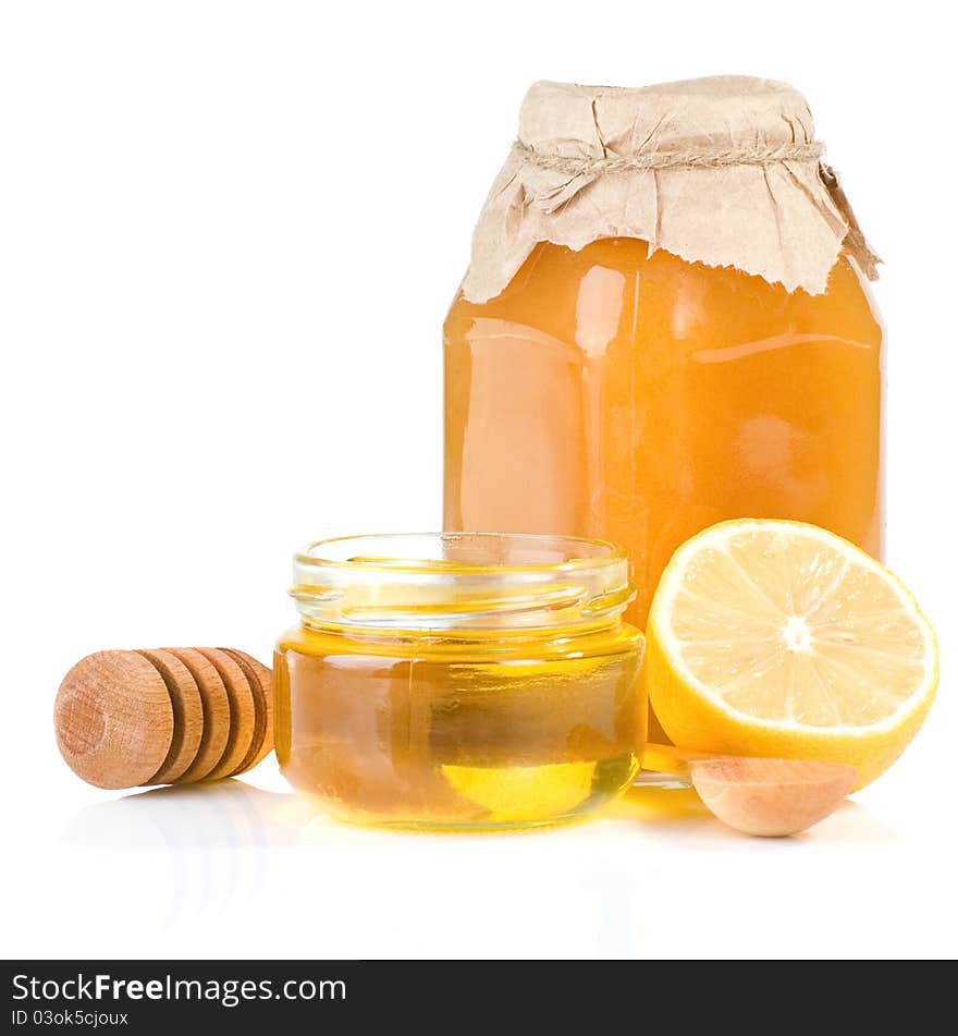 Jar full of honey and lemon on white background