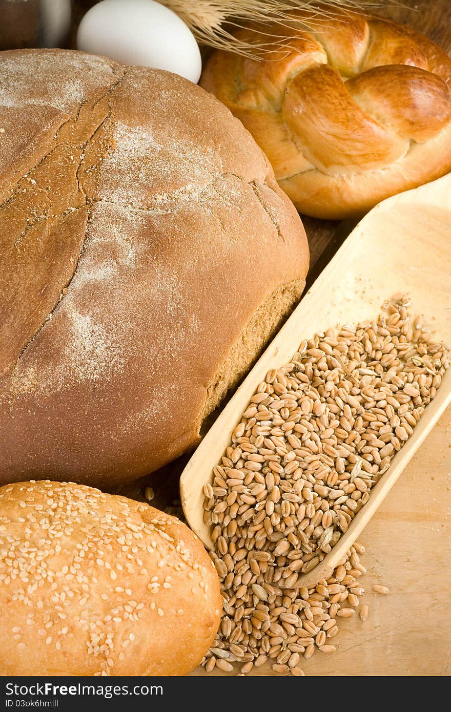 Bakery products and wheat grain on wooden texture