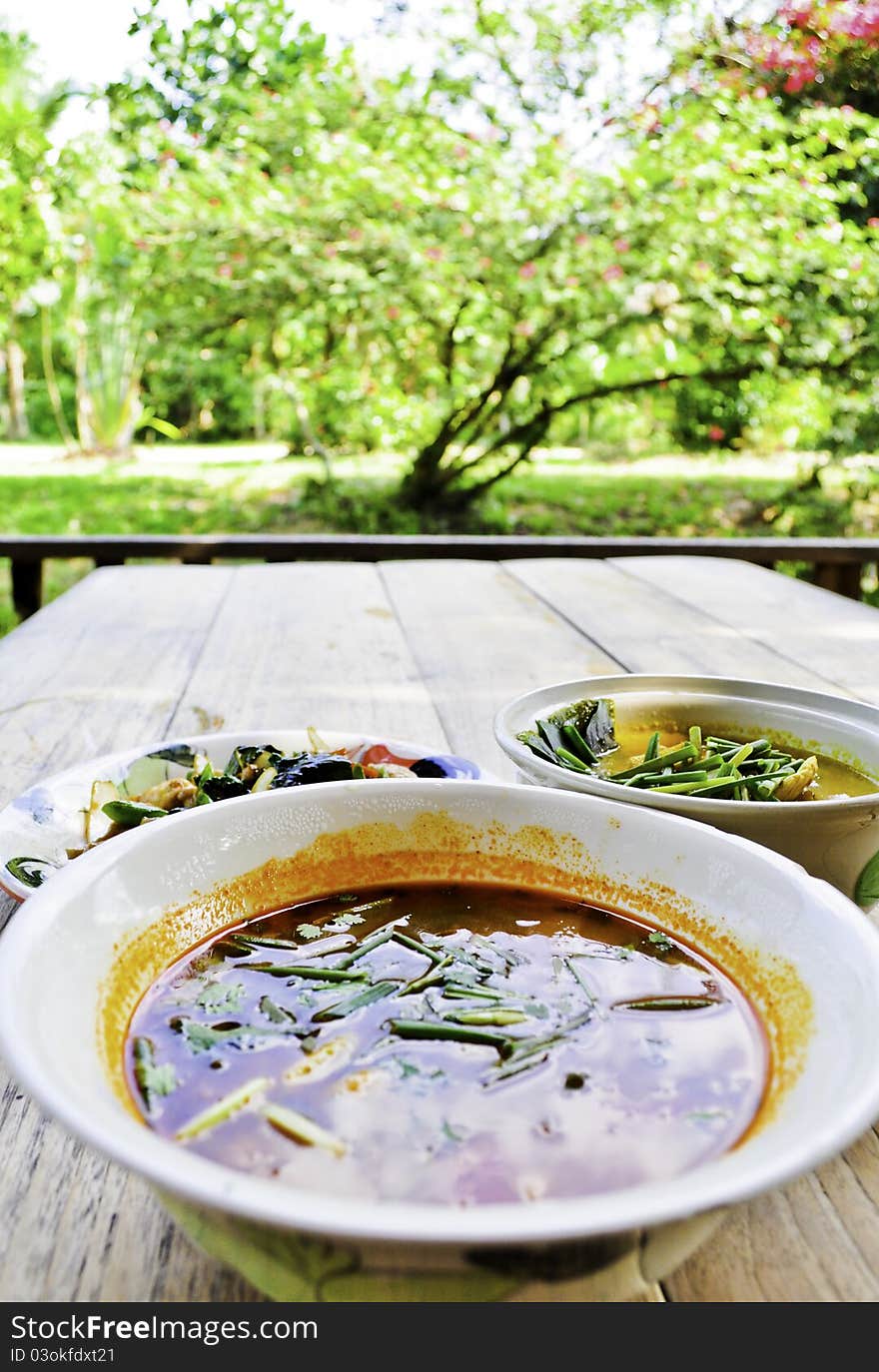 A bowl tom yum soup in a garden picnic area. A bowl tom yum soup in a garden picnic area