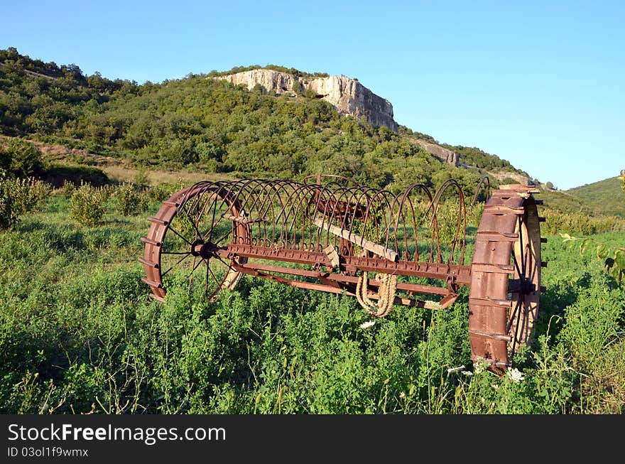 Abandoned harrow in field near mountain