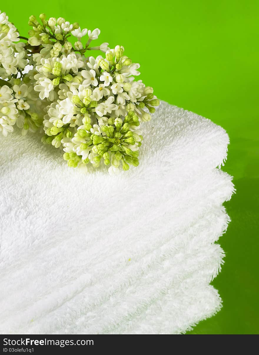 Pile white towels on green background and branch white lilac