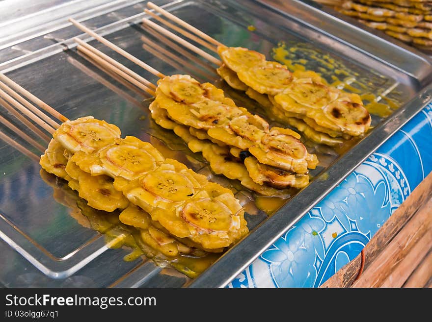 Grilled bananas stack with sticks with sweet sauce on metal plate. Grilled bananas stack with sticks with sweet sauce on metal plate