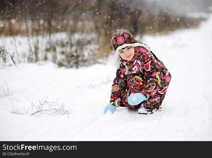 Child girl in colorful snowsiut plays outdoors in snowfall. Child girl in colorful snowsiut plays outdoors in snowfall