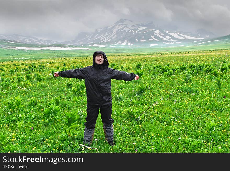 Summer landscape with tourist, green grass, mountains and clouds