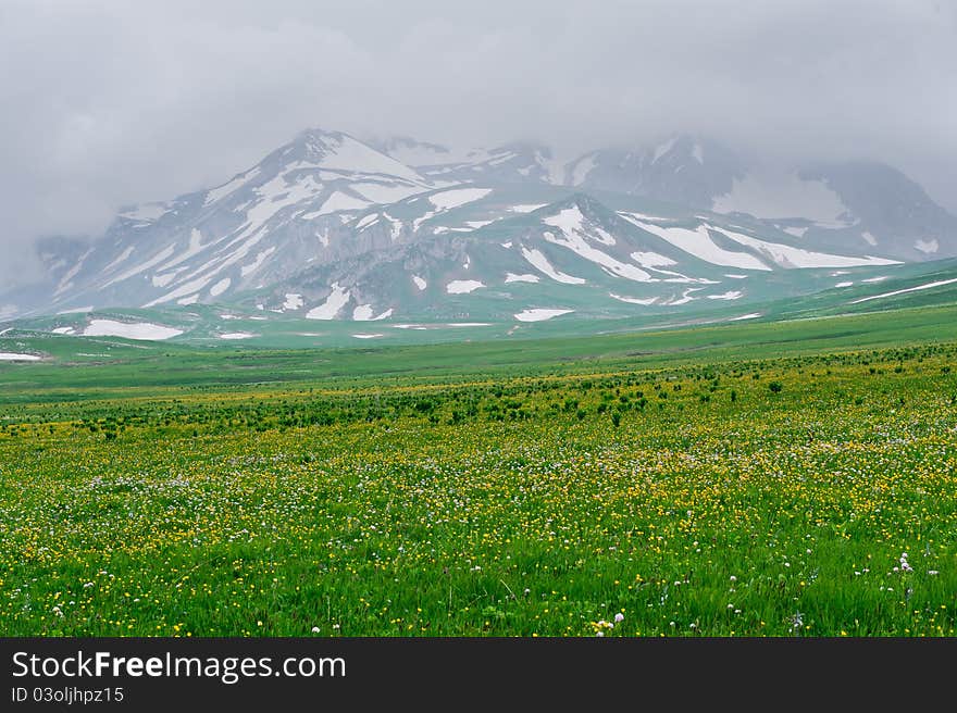 Summer landscape with green grass, mountains and clouds. North Caucasus mountains