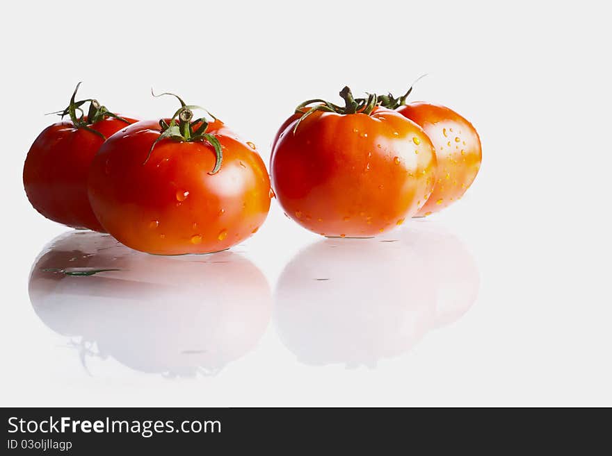 Fresh and wet biological tomatoes witrh reflaction on white.