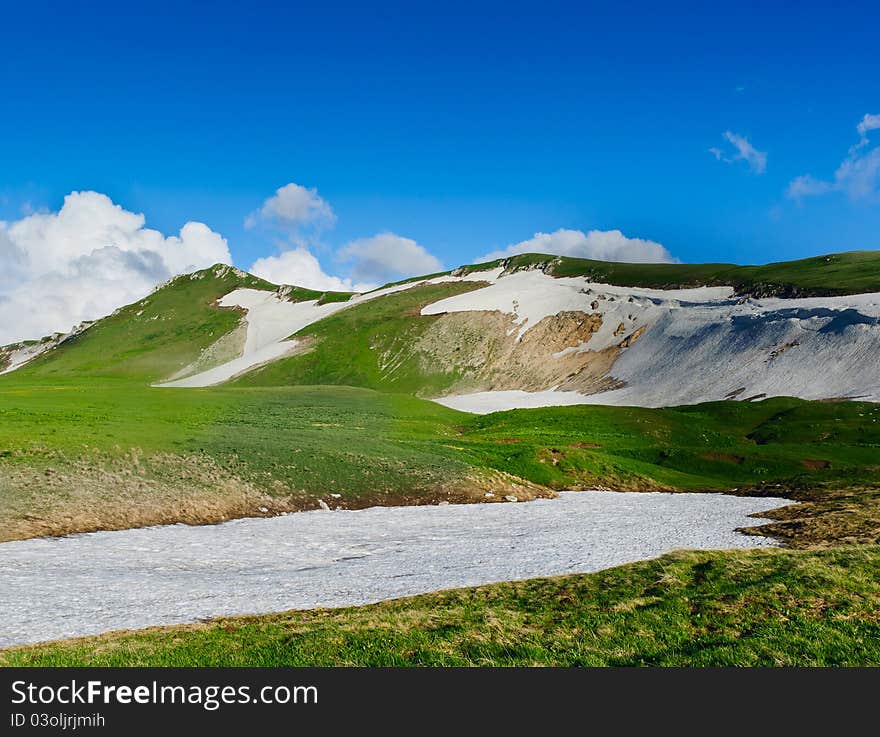 Summer landscape with green grass, mountains and clouds. North Caucasus mountains. Summer landscape with green grass, mountains and clouds. North Caucasus mountains