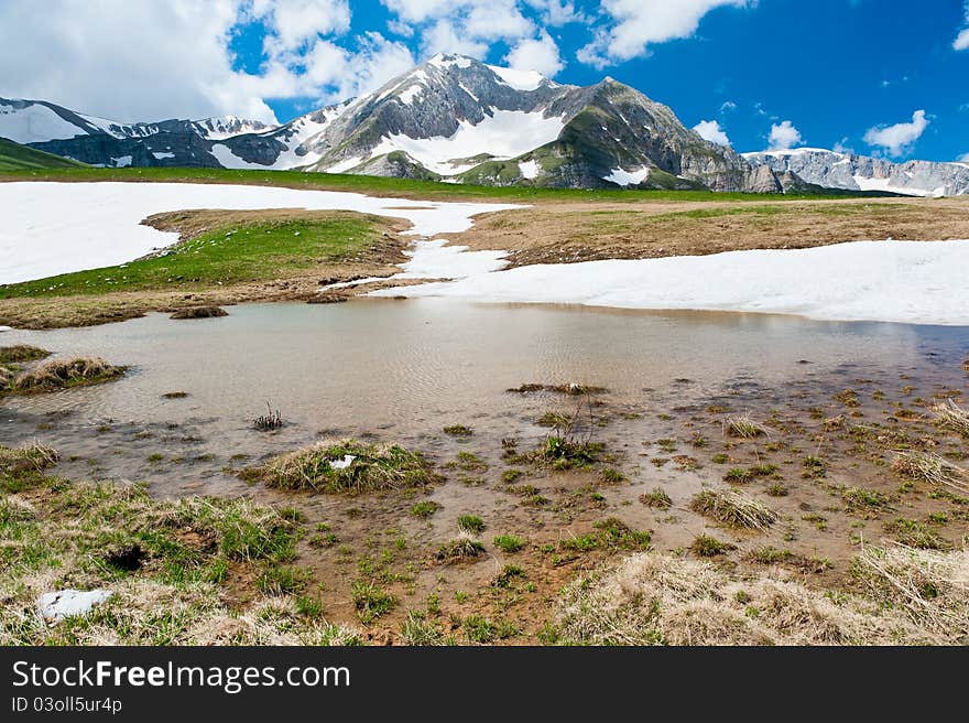 Summer landscape with green grass, mountains and clouds. North Caucasus mountains. Summer landscape with green grass, mountains and clouds. North Caucasus mountains