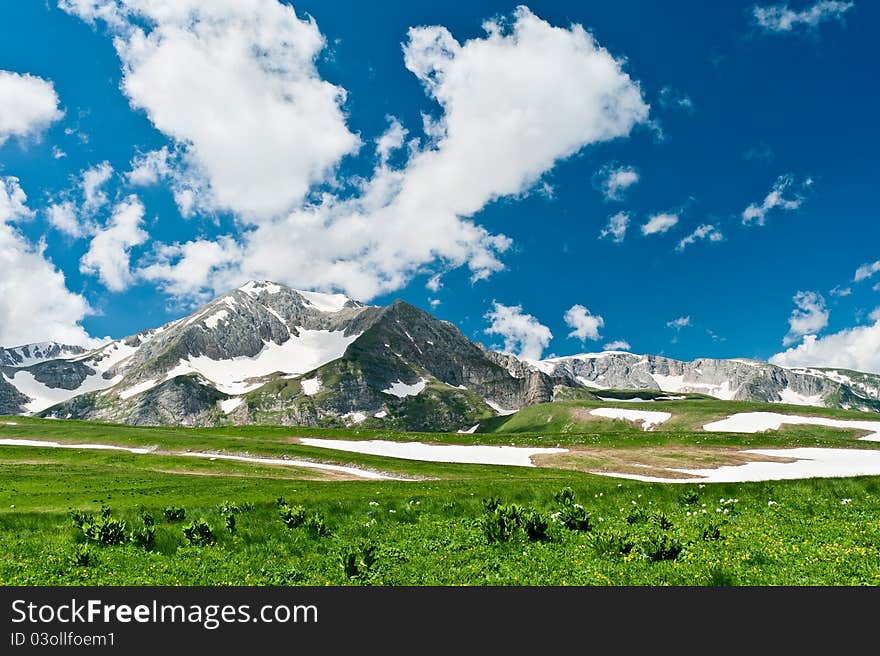 Summer landscape with green grass, mountains and clouds. North Caucasus mountains. Summer landscape with green grass, mountains and clouds. North Caucasus mountains