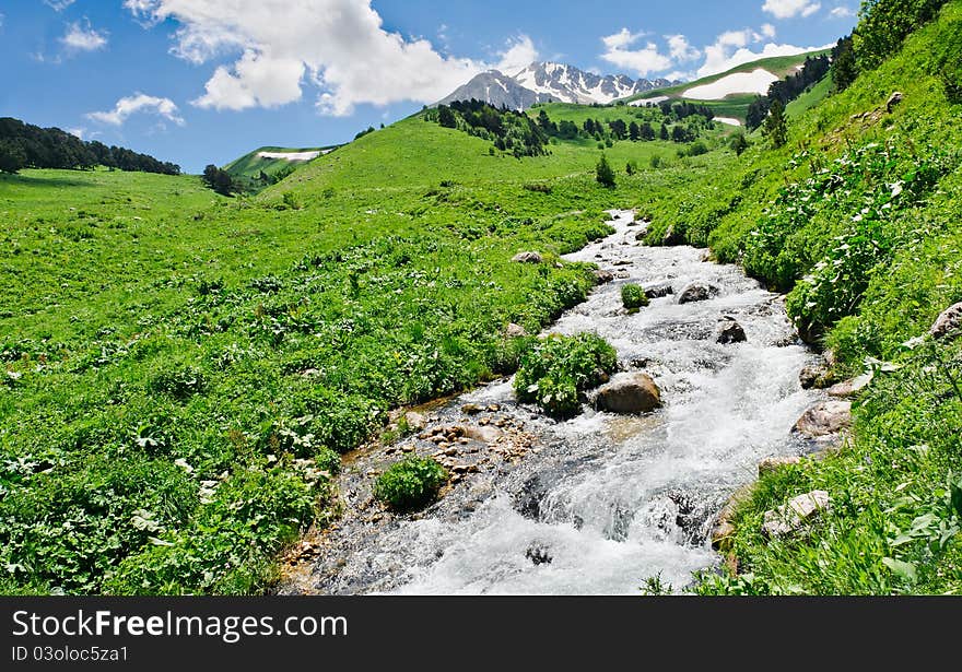 Summer landscape with green grass, mountains and river. North Caucasus mountains. Summer landscape with green grass, mountains and river. North Caucasus mountains