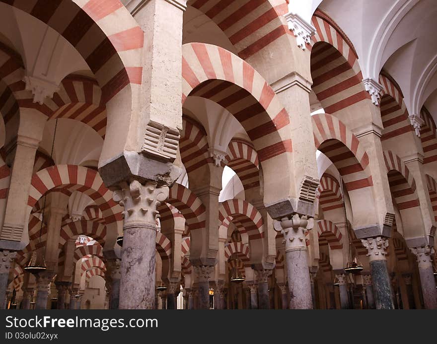 Red and white arches sit above numerous pillars in the famous Mezquita cathedral in Cordoba, Spain. Red and white arches sit above numerous pillars in the famous Mezquita cathedral in Cordoba, Spain.