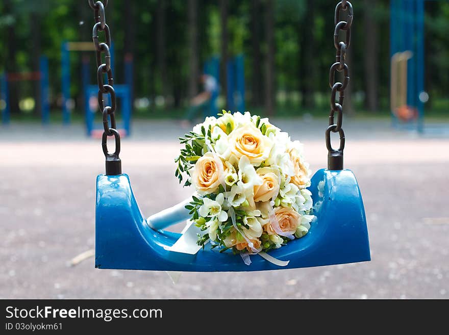 Wedding bouquet on blue swing in park