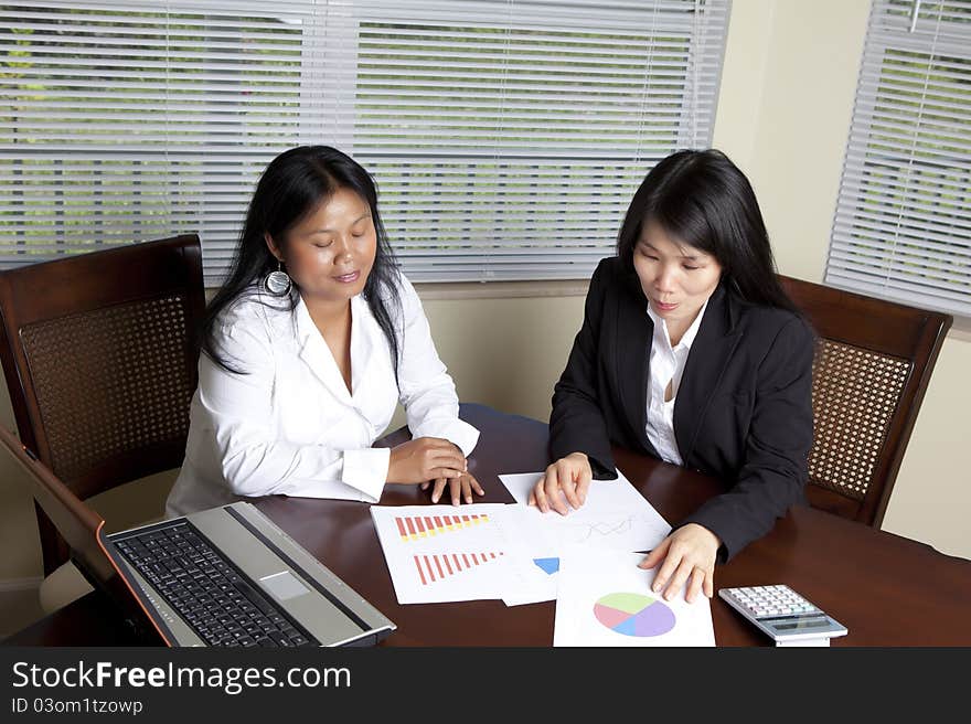 Two Asian Business women working at a desk.