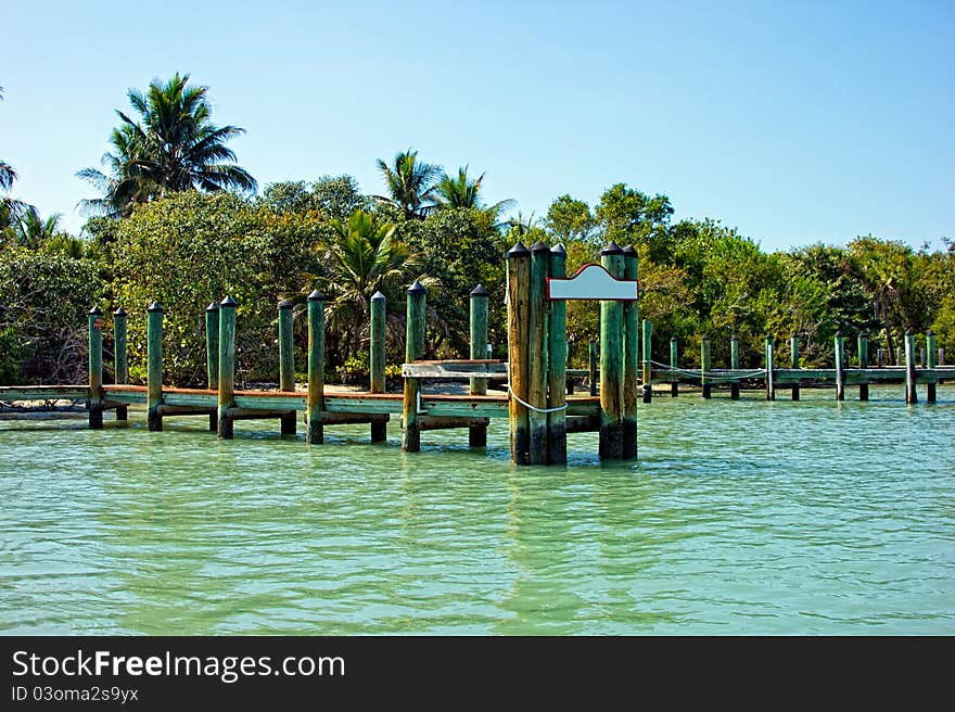 Old wooden pier with blank sign in tropics