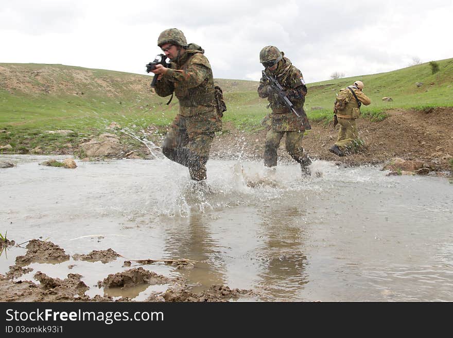 Military men crossing the river under fire. Military men crossing the river under fire