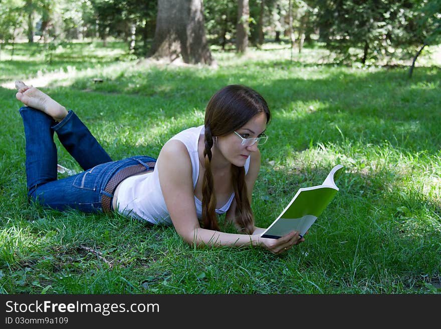 Student Girl Reading A Book On The Grass