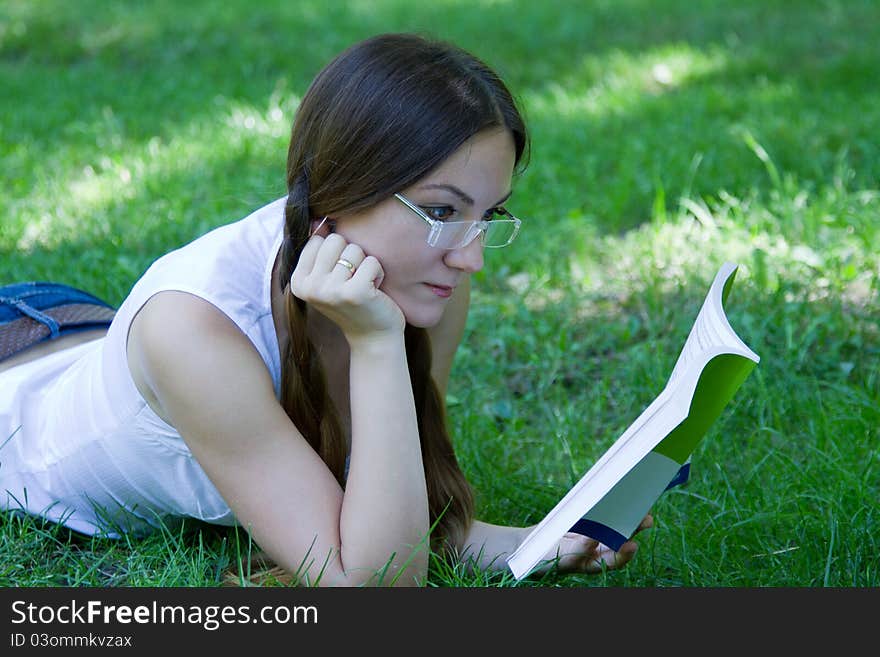 Business woman reading a book on the grass