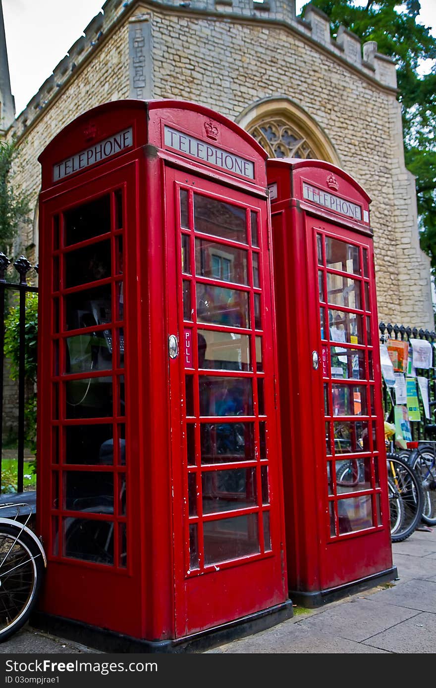 2 red phone box's stand in front of an old church in Cambridge UK.