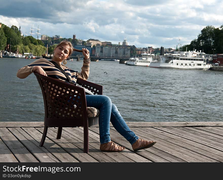 Beautiful girl sitting in a chair on the pier. Beautiful girl sitting in a chair on the pier