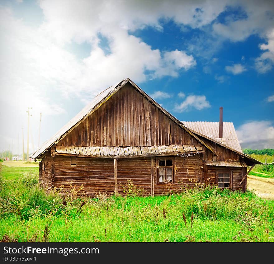 Vintage wooden house in the countryside over blue sky with artistic lights and shadows added