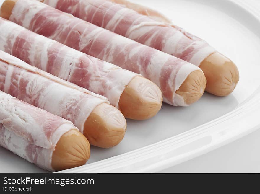 Raw bernese sausages on a plate on white background