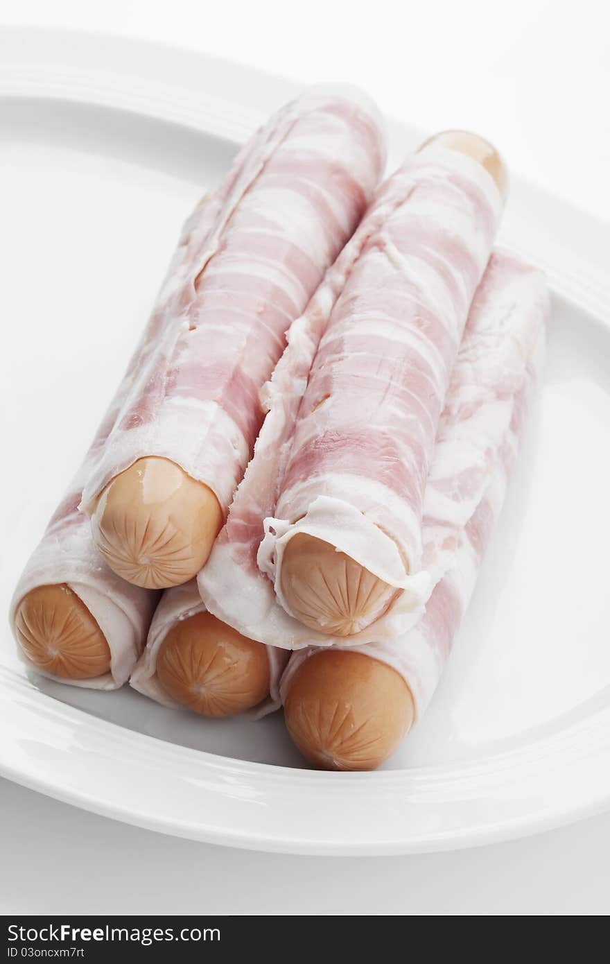 Raw bernese sausages on a plate on white background