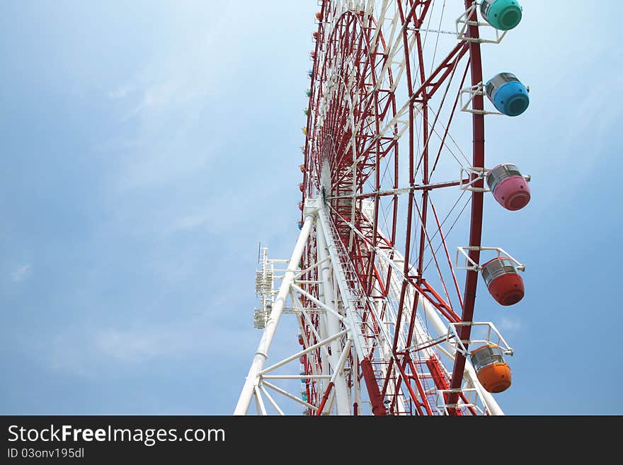 Low angle view of ferris wheel with colorful gondolas and blue sky background. Photo taken on: Aug 8, 2011 in Japan