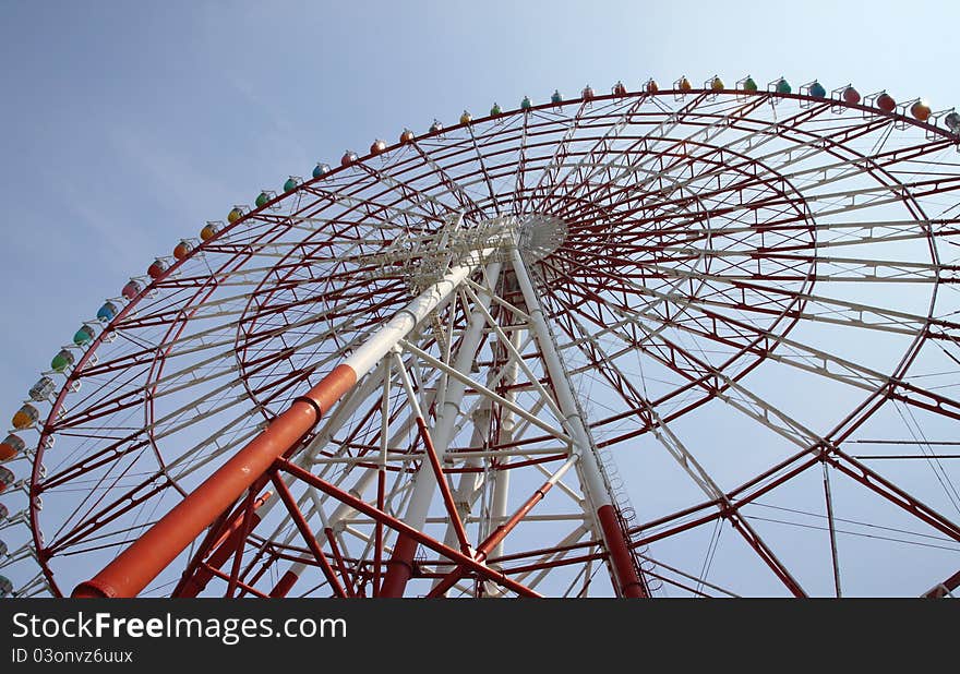 Low angle view of ferris wheel with colorful gondolas and blue sky background. Photo taken on: Aug 8, 2011 in Japan