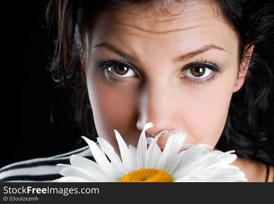 Beautiful young woman with chamomile in hand on black