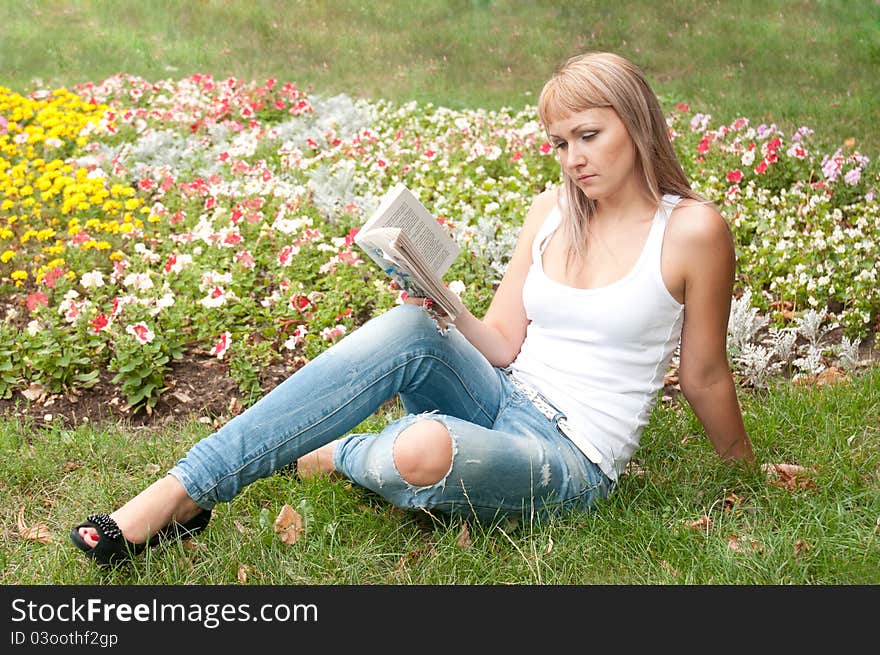 Girl Sitting In The Garden And Reading A Book