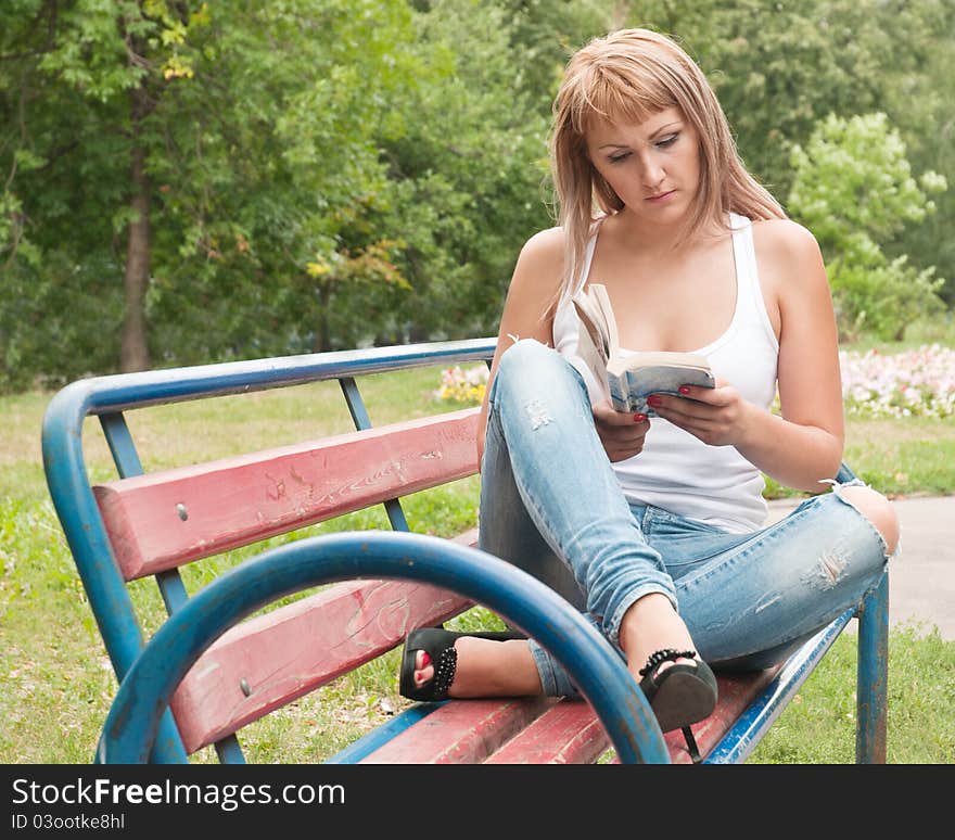 Young girl in a park reading a book. Young girl in a park reading a book