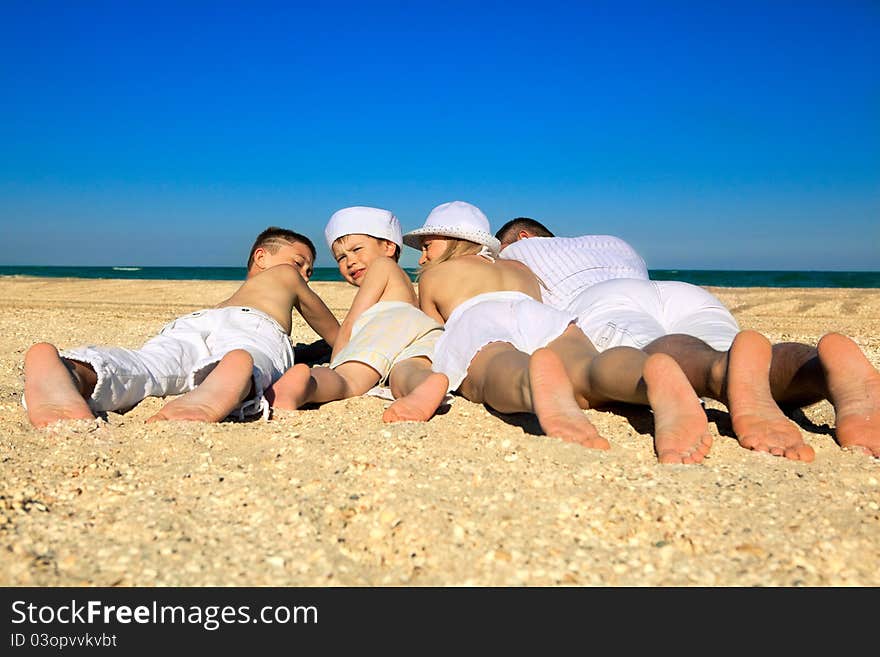 Photo of  family lying on sand on background of blue sky