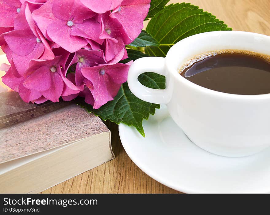 Cup of coffee, book and pink hydrangea .