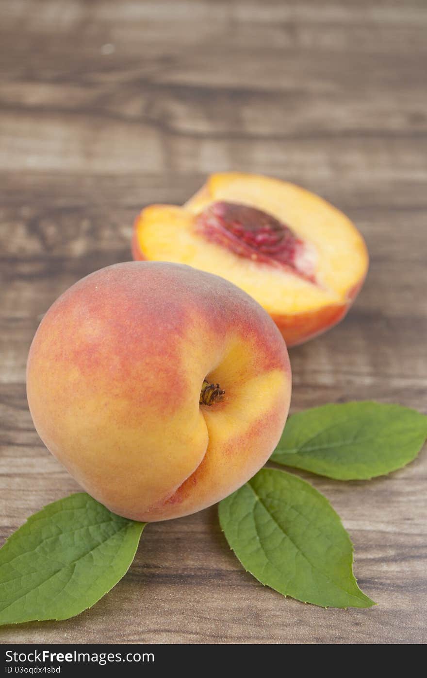 Ripe peach with leaf on wood background